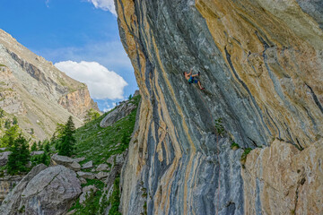 LOW ANGLE VIEW: Experienced climber with strength and concentration holds a grip on overhanging...