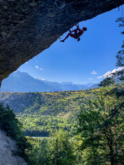 LOW ANGLE VIEW, SILHOUETTE: Sport climber in the middle of an overhang with stunning panoramic view...