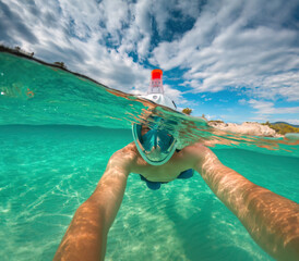 A man with mask and snorkel snorkeling in the blue turquoise sea water and enjoy underwater swimming
