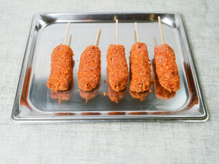 Five fancy kebabs on wooden sticks on stainless steel tray and light color table cloth. Barbeque...