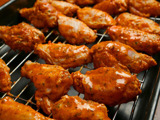 Cooking fresh chicken wings on an oven. The product is covered in red Asian style sauce and ready for cooking in high temperature. Party finger snack food.