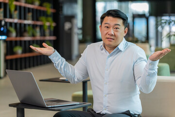What. Why. Angry Chinese businessman raising hands in indignant expression, asking reason of...