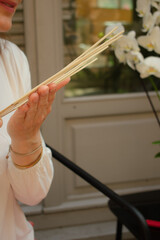Woman with closed eyes, deeply inhaling the calming scent of incense sticks, ready to infuse a...