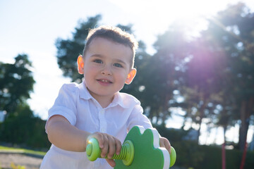 A little boy is playing on the playground. Rocking back and forth with laughter.