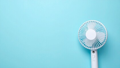 穏やかな青の空間に小さく佇む電動ファンが夏の静けさと清涼感を伝えるミニマル表現

