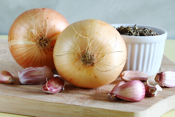 Brazilian seasoning on the cutting board. Onions and garlic cloves.