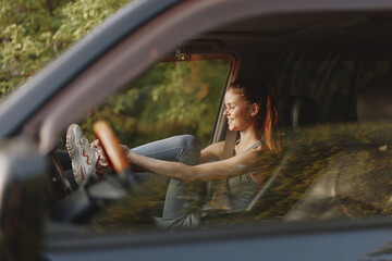 Happy young woman enjoying a road trip, smiling in car, wearing casual workout clothes, with...
