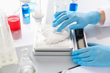 Scientist weighing sample on scales at white mirror table, closeup