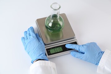 Scientist weighing sample on scales at white table, closeup
