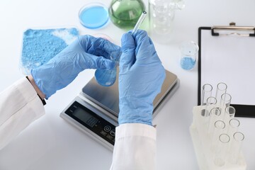 Scientist working with sample and scales at white table, closeup