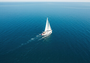 Fototapeta premium Top view of a white boat sailing in the blue sea