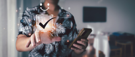 Guest satisfaction concept. Man in shirt using smartphone at hotel and pointing at glowing check mark on virtual interface to indicate satisfaction with service.