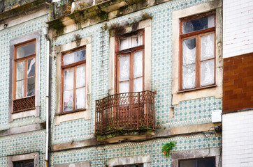 Weathered Elegance and Faded Glory at Old Building Facade with Traditional Azulejo Tiles, Weathered Wooden Windows, and Rusty Balcony in the old town of Porto
