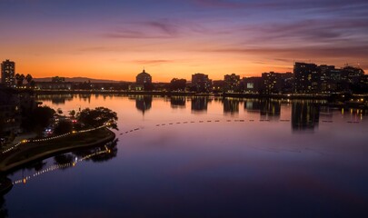 Oakland, USA, skyline at dusk reflects in Lake Merritt. The city lights begin to twinkle as the sky...