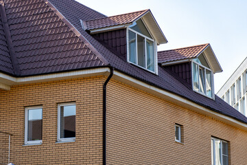 Exterior architecture featuring a brick house with a brown roof and dormer windows