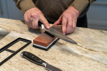 Sharpness concept: Close-up of hands sharpening a knife on a whetstone