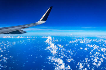 airplane wing flying over the sea with white clouds in Mexico