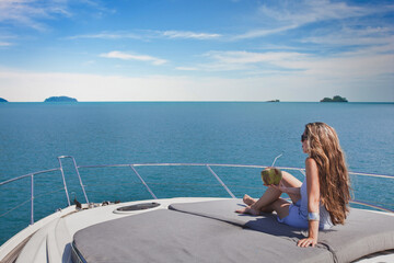 woman relaxing onboard of luxury yacht on sea cruise, vacation travel, drinking coconut in summer, sunbathing