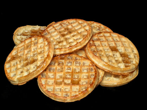 Stack of syrup-covered frozen waffles on black background