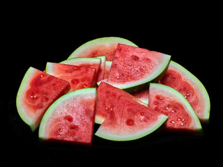 Pile of fresh watermelon slices on black background