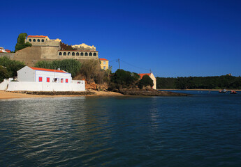 Portugal, Alentejo, Vila Nova de Milfontes. The River Mira estuary overlooked by Saint Clement's Fort - Forte de Sao Clemente and an old beach house in the foreground. Built between 1599 and 1602.