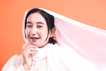 Elegant Woman in White Shawl Smiling, Studio Portrait: Isolated on a orange background, showcasing serene beauty and cultural elegance.