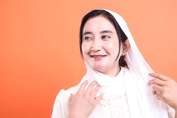 Portrait of a Smiling Muslim Woman in Hijab: Radiance and Serenity, gracefully isolated on a orange...