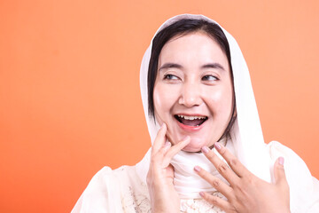 Joyful Muslim Woman with Headscarf: A Portrait of Happiness and Faith, isolated on a orange background, evoking warmth and positive emotions.