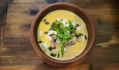 Delicious pumpkin soup in a brown clay bowl on the table