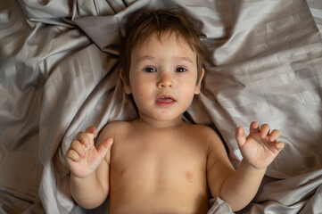 Top view of cute caucasian toddler lying in bed. 