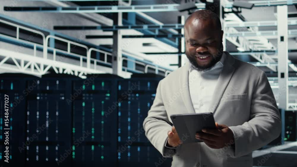 Poster close up of technician walking in data center, using tablet to check equipment for system stability.