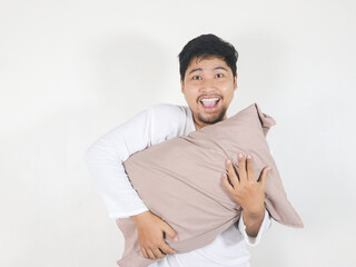 Handsome Asian man who just woke up showing excited gesture while pointing to the side and holding...