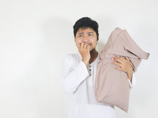 handsome asian man who just woke up holding a pillow and showing a scared face while biting his...