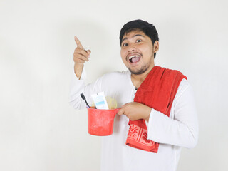 Handsome Asian man is going to take a bath and carrying toiletries placed on the ladle he is...