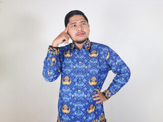 Indonesian civil servant man showing a thinking gesture, looking sideways, and putting his hand on...