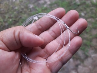 Hand Holding Fishing Line and Hook