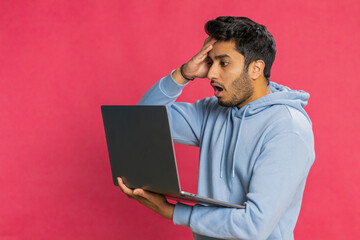 Displeased Indian man use laptop notebook typing browsing working, loses becoming surprised by...