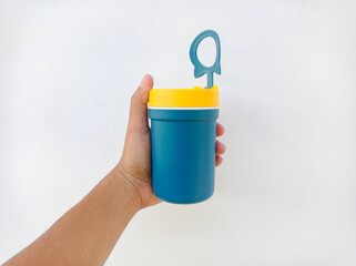 Blue container with yellow lid held in hand