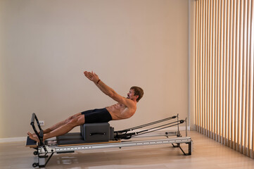 A man doing Pilates on a reformer. 