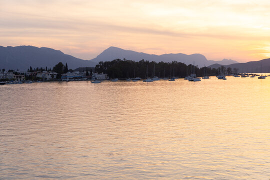Panoramic view of luxury yachts moored in the bay during sunset with mountain range in the background