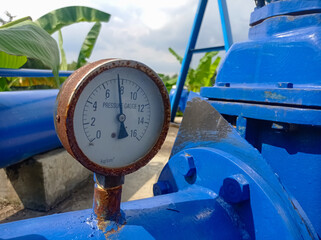 Industrial pressure gauge on blue pipeline