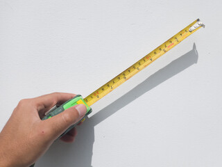 Measuring tape extending from hand on wall