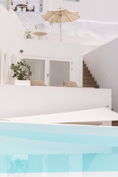 Upscale and minimal boutique hotel with white walls and light blue pool in Santorini, Greece