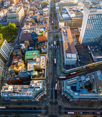 Aerial view of Oxford Street in London with bustling traffic, classic buildings, and red double-decker buses on a sunny, clear day.