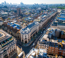 Aerial view of Regent Street in London with its sweeping curve, elegant architecture, red buses, and busy city streets on a clear day.