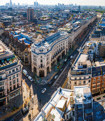 Aerial view of Regent Street in London with its sweeping curve, elegant architecture, red buses, and busy city streets on a clear day.