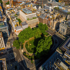 Aerial view of Hanover Square in London featuring green park space, surrounding classic architecture, and city streets on a clear day.
