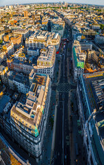 Aerial view of Regent Street in London with its sweeping curve, elegant architecture, red buses, and busy city streets on a clear day.