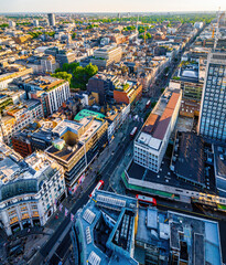 Aerial view of Oxford Street in London with bustling traffic, classic buildings, and red double-decker buses on a sunny, clear day.