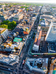 Aerial view of Oxford Street in London with bustling traffic, classic buildings, and red double-decker buses on a sunny, clear day.